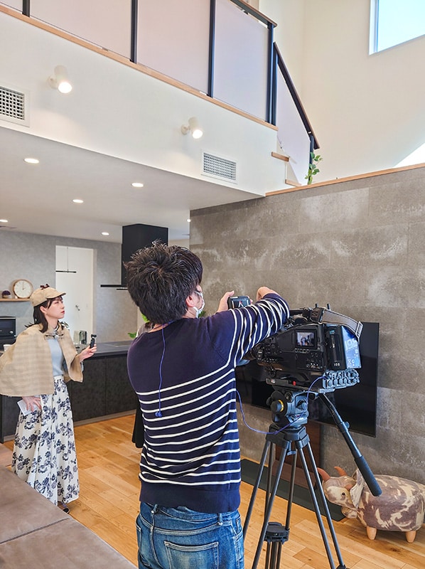 モデルハウス室内でテレビ取材が行われている様子。カメラマンとリポーターが撮影中。