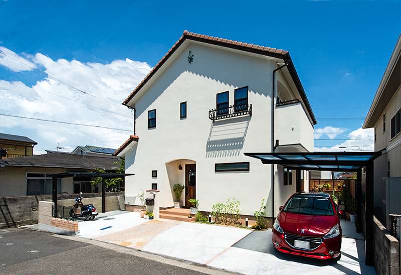 注文住宅の施工例写真で淡いクリーム色の壁に濃茶色の洋瓦の外観