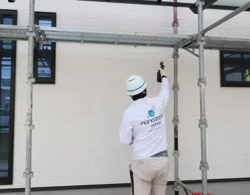 作業員が北側外壁にナノゾーンコートをスプレーガンで吹き付けている施工中の様子
