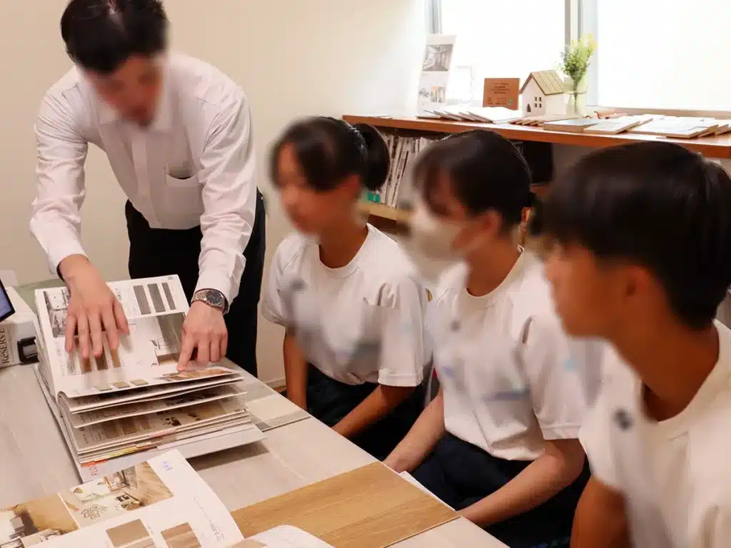 中学生3名が壁紙やインテリア素材について説明を受けている様子